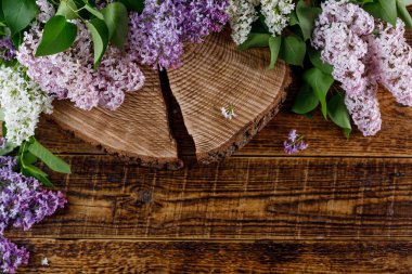 Ahşap bir eflatun çiçekler bir saçılma tarafından çevrili içinde güzel bir çatlak ile yattım. Natürmort ahşap arka plan üzerinde.