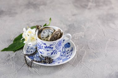 Rafine bir fincan yeşil çay ile Yasemin ve üzerinde bir zinciri içinde güzel bir saat. Çay vakti.