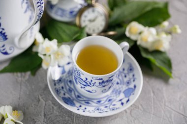 Çiçeklenme hassas Yasemin çiçekleri ve yeşil çay zinciri içinde belgili tanımlık geçmiş bir mekanik saat ile.