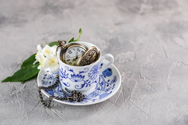 Rafine bir fincan yeşil çay ile Yasemin ve üzerinde bir zinciri içinde güzel bir saat. Çay vakti.