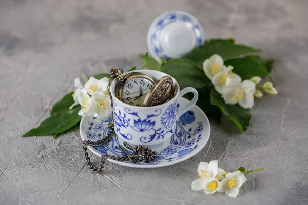 Bir nazik natürmort bir fincan yeşil çay ve Yasemin çiçekleri ile. Bir fincan bir saat ampul.