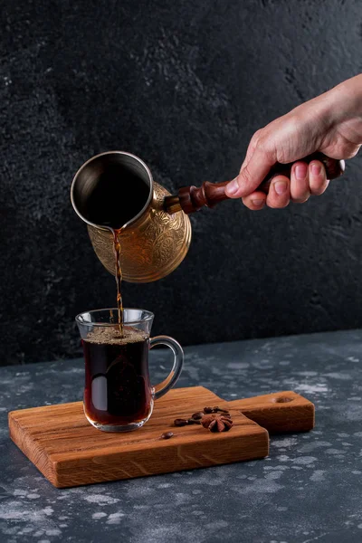Geleneksel Türk kahvesi ile ahşap arka plan üzerine bir kafede dökme el. Kupası ve pot kahve ve kahve çekirdekleri bir ahşap tahta üzerinde.