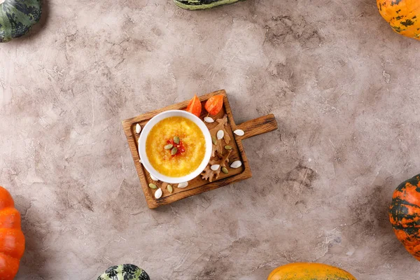 Pumpkin soup on a neutral wooden board in a frame of pumpkin and zucchini vegetables. — Stock Photo, Image