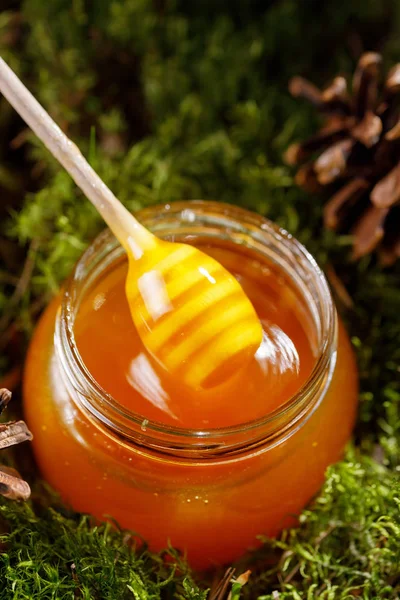 Μέλι ραβδί scooping ευωδιαστό μέλι από ένα γυάλινο βάζο. — Φωτογραφία Αρχείου