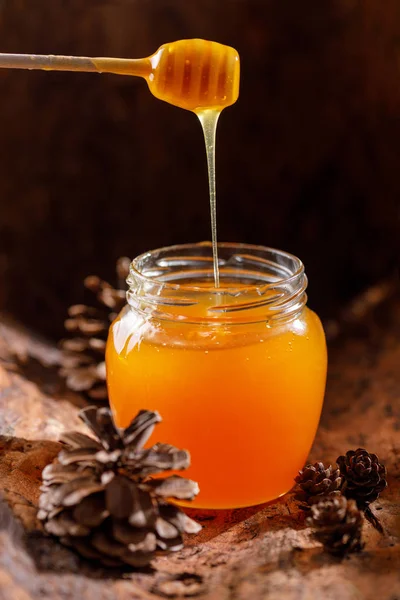 木のスプーンで美しいガラスの瓶に流れ込む新鮮な香りの蜂蜜 クローズ アップ — ストック写真