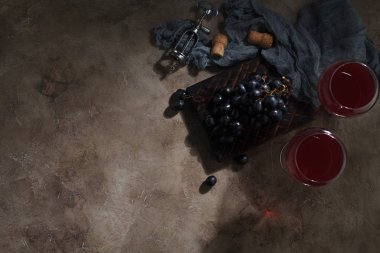 Kırmızı şarap cam kadehler üzüm ve vintage tirbuşon dokulu arka plan üzerine kurulu. Metin için yer ile üstten görünüm.