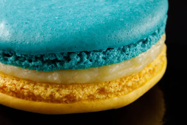 Appetitliche Zweifarbige Macarons Blau Und Gelb Auf Schwarzem Hintergrund Nahaufnahme — Stockfoto