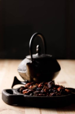 Dökme demir tencere ve bir dekoratif ahşap tahta üzerinde kuru kalça. Sağlık ve vitaminler kavramı. Çay ile natürmort.