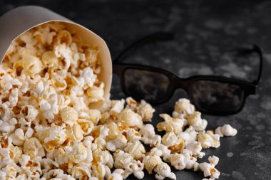 Film izlemek için çerez. Bir kova patlamış mısır karanlık bir arka plan ve gözlük. Yakın çekim.