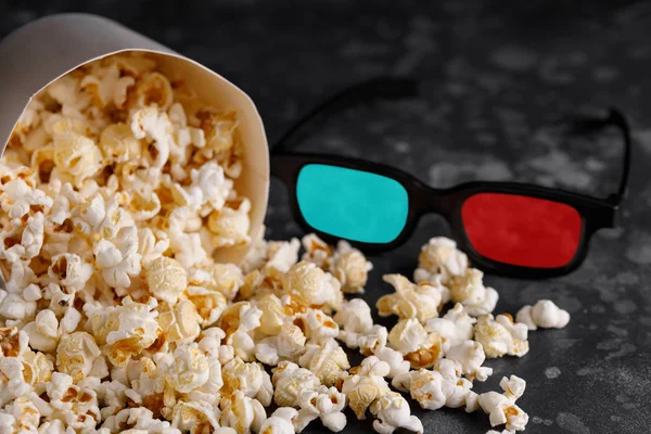 Snack for watching movies. A bucket of popcorn on a dark background and 3 d glasses. Close-up.