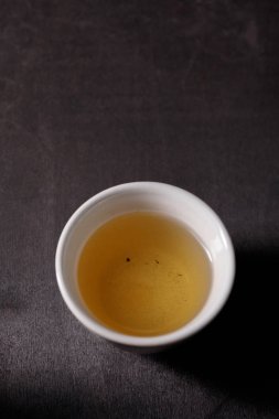 Piala ile vitamin içeceği karanlık bir arka plan üzerinde otlar üzerinde taze demlenmiş. Yakın çekim.