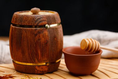 Bal içinde ve karanlık bir arka plan üzerinde ahşap bir masa üzerinde bir kaşık ile namlu. Yakın çekim. Rustik natürmort.