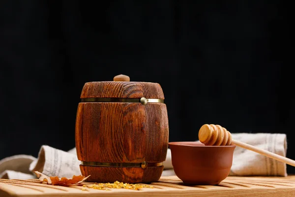 蜂蜜の中や暗い背景に木製のテーブル スプーンと小さな木製の樽 バレルのクローズ アップ 素朴な静物 — ストック写真