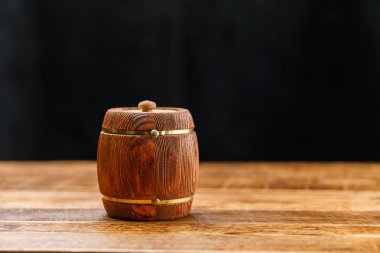 Karanlık bir arka plan üzerinde ahşap bir masaya bal ile namlu. Yakın çekim.