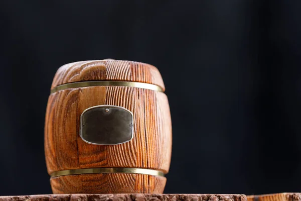 Closed wooden keg with honey on a wooden saw on a dark background. Barrel. Copy space. Close-up.