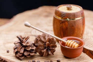 Varil ile bal ve bir büyük bir kaşık ahşap ve çam kozalakları. Dokulu ağaç ürünleri. Yakın çekim.