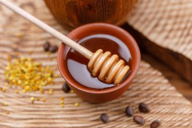 Bir ahşap dokulu arka plan ve sopa ile parlak bir kase kokulu bal polen. Yakın çekim.