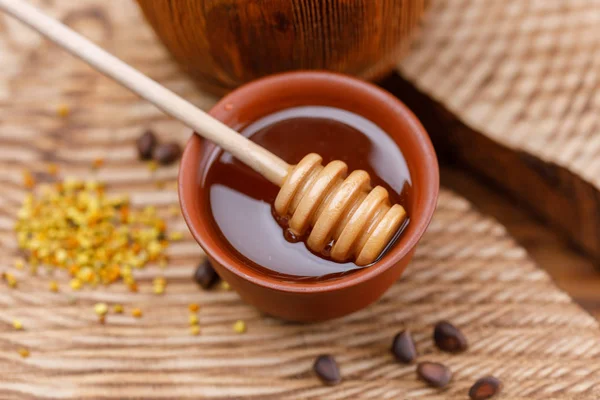 Bir ahşap dokulu arka plan ve sopa ile parlak bir kase kokulu bal polen. Yakın çekim.