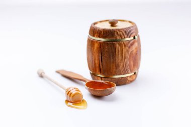 Varil ve tahta kaşık ve sopa ile beyaz bir arka plan üzerinde tatlım. İzole. Yakın çekim.