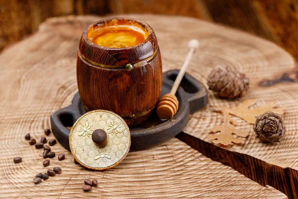 Open barrel with honey on a wooden saw and cedar cones. Rustic.