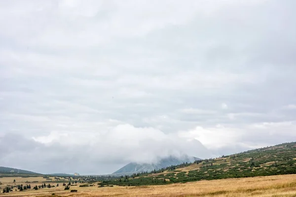 Snezka, Krkonose, border of Poland and Czech Republic. Beautiful panoramic view of the mountain. Peak of the mountain in the fog on the cloudy sky won. Amazing view for a postcard or calendar.