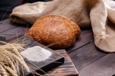 Gevrek el yapımı somun bir tahta üzerinde tam tahıllı rustik ekmek un ile kaplı. Natürmort. Rustik.