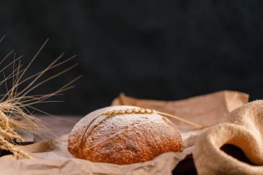 Zanaat ekmek ve spikelets yakın çekim karanlık bir arka plan. Sağlıklı gıda ve geleneksel ekmek kavramı. Rustik.