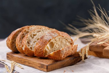 Karanlık bir arka plan üzerinde kurulu yakın çekim üzerinde zanaat ekmek dilimlenmiş. Sağlıklı gıda ve geleneksel ekmek kavramı. Rustik.
