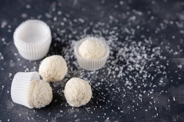 Hindistan cevizi pasta kavramı. Hindistan cevizi Tepesi ve hindistancevizi karanlık bir arka plan üzerine beyaz çikolata topu şekerle.