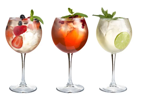 Alcoholic and non-alcoholic cocktails with mint, fruits and berries on a white background. Three cocktails in glass glasses on a long leg. Isolated.
