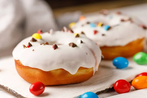 Concepção de culinária, cozimento e comida - close-up. Donuts em esmalte branco com dragee cor em uma placa decorativa . — Fotografia de Stock