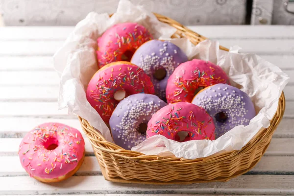Концепція приготування їжі, випічки та їжі крупним планом. Рожеві та фіолетові пончики у плетеному кошику у формі серця. Кольори тенденції . — стокове фото
