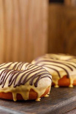 Kavramı, pişirme, pişirme ve gıda - yakın çekim. İki donut ile çikolata dekorasyon dekoratif bir tahta üzerinde sarı bir sır.