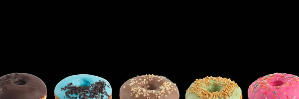 Appetizing donuts with multi-colored icing on a black background. Isolated. Banner. — Stock Photo, Image