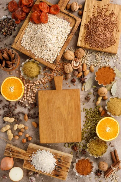 Dried fruits cereals spices and nuts organic healthy snacks on a textural background. The concept of healthy eating. Lenten products. Wooden decorative board with a place under the text. Copy space.