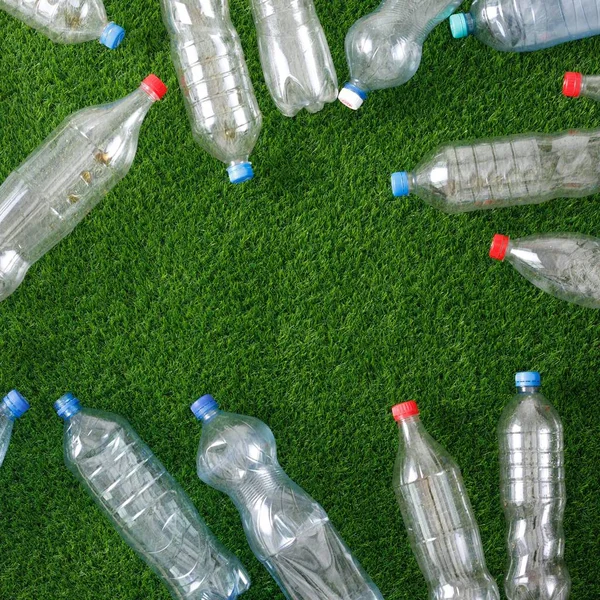 The concept of recycling plastic and environmental protection. Pet preforms for plastic bottles on the green grass. Artificial turf.