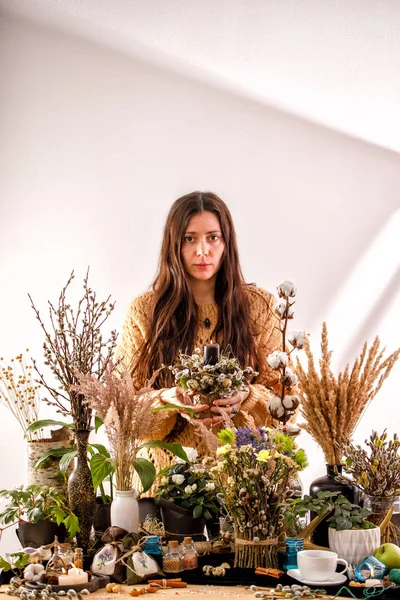 Still life with dry flowers and willow branches on a wooden table. Decor candles, dry branches of willow and a girl on the background. The concept of a traditional Russian holiday Palm Sunday.