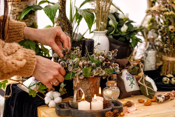 Stilleven met droge bloemen en wilgentakken op een houten tafel. Decor kaarsen, droge wilgentakken en een vrouwelijke hand op de achtergrond. Het concept van de Russische vakantie Palm zondag. — Stockfoto