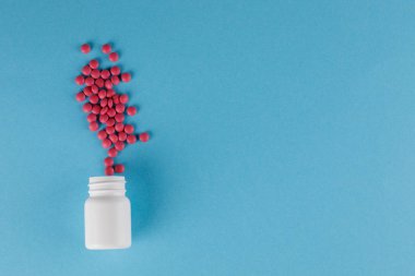 Ambalaj hapları. Bir sürü hap. Mavi bir arka plan üzerinde bir kavanoz dan dökülen haplar.