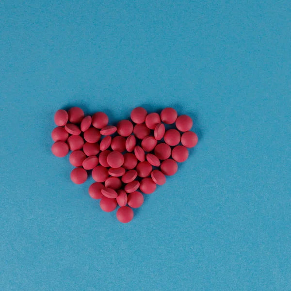 파란색 배경에 심장의 형태로 빨간 알약의 산란. 사각형. — 스톡 사진