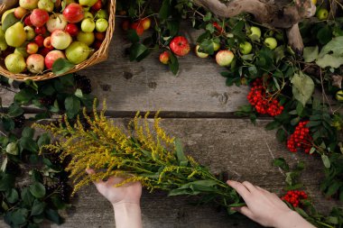 Ahşap bir arka plan üzerinde sonbahar elma ve armut Çerçeve. Yukarıdan görüntüleyin. Ellerinde sonbahar çiçekleri. Kopya alanı. Hasat konsepti.
