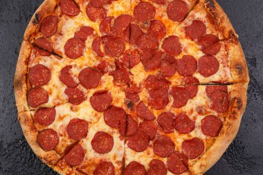 Siyah dokusal arka plan üzerinde geleneksel piperoni pizza. Yakın