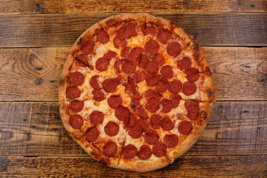 Ahşap masaüzerinde geleneksel piperoni pizza. . Lezzetli gıda kavramı.