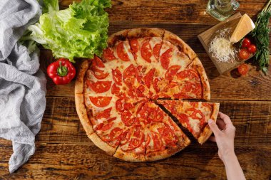 Pizza Margarita tahta bir masada. El ve malzemelerle natürmort.