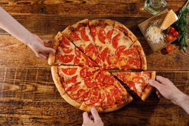 Pizza Margarita tahta bir masada. Eller ve malzemelerle natürmort.