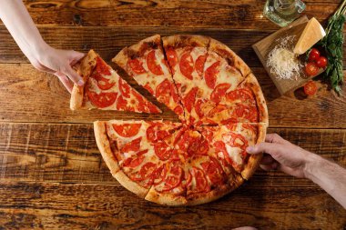 Pizza Margarita tahta bir masada. Eller ve malzemelerle natürmort.