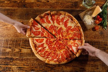 Pizza Margarita tahta bir masada. Eller ve malzemelerle natürmort.