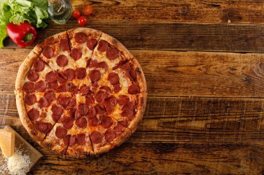 Tahta bir masada Pepperoni pizzası. Malzemelerle natürmort. Üst te. Kopyalama alanı.