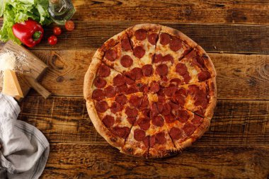 Tahta bir masada Pepperoni pizzası. Malzemelerle natürmort.