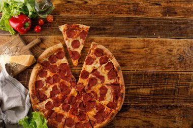 Tahta bir masada Pepperoni pizzası. Malzemelerle natürmort. Üst te. Kopyalama alanı.